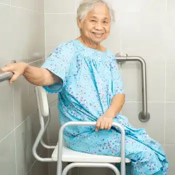 A woman using a shower chair and bathroom safety rails