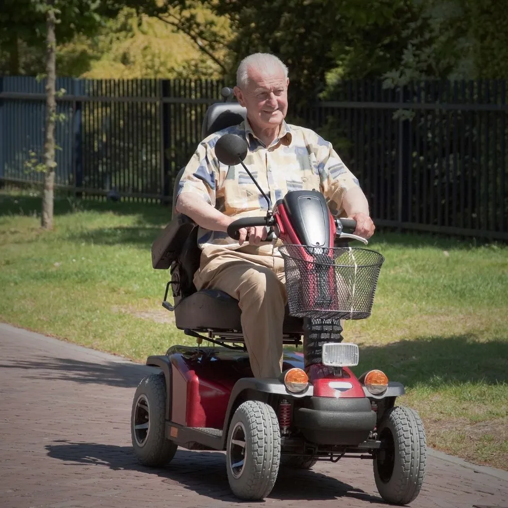 An older man riding a mobility scooter outdoors