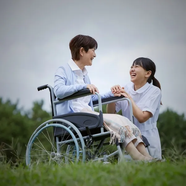 A woman in a wheelchair spending time outdoors with a caregiver