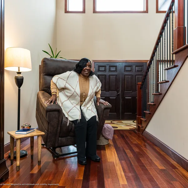 A woman standing up with support from a lift chair at home